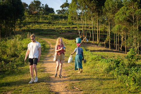 Lake Bunyonyi, Uganda: Two tourists and a native passing on a pathway on an island of Lake Bunyonyi