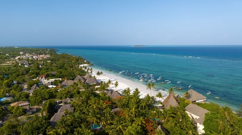 High aerial view of Matemwe Beach in Zanzibar with turquoise waters, palm trees, and anchored boats