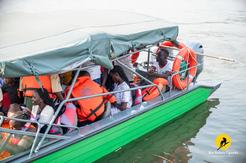 Green speedboat with orange life jackets and gray canopy carrying multiple passengers on water