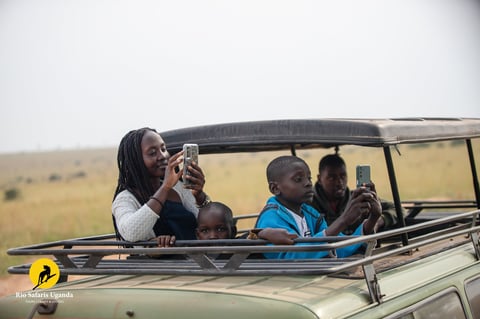 Tourists on safari vehicle taking photos of wildlife in African savanna landscape