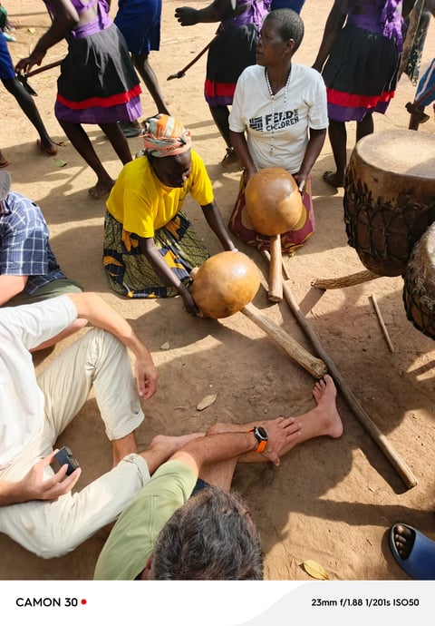 People gathered in a circle playing traditional drums during a cultural activity or ceremony outdoors