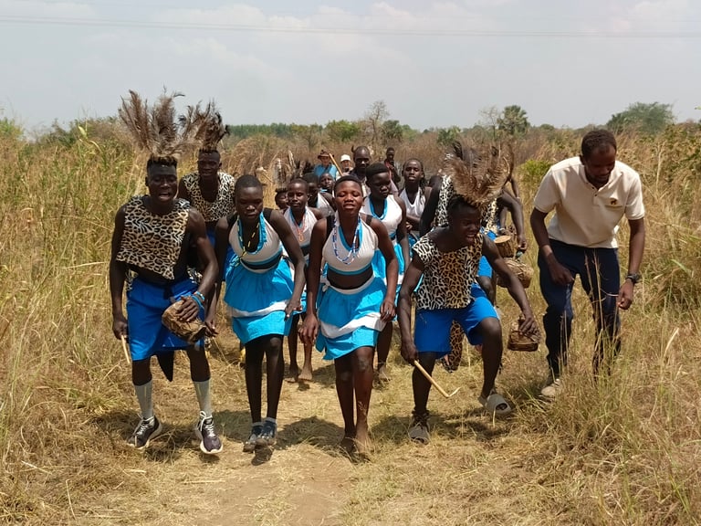 Group of African children and adults wearing blue shirts running together on a dirt path through dry grassland