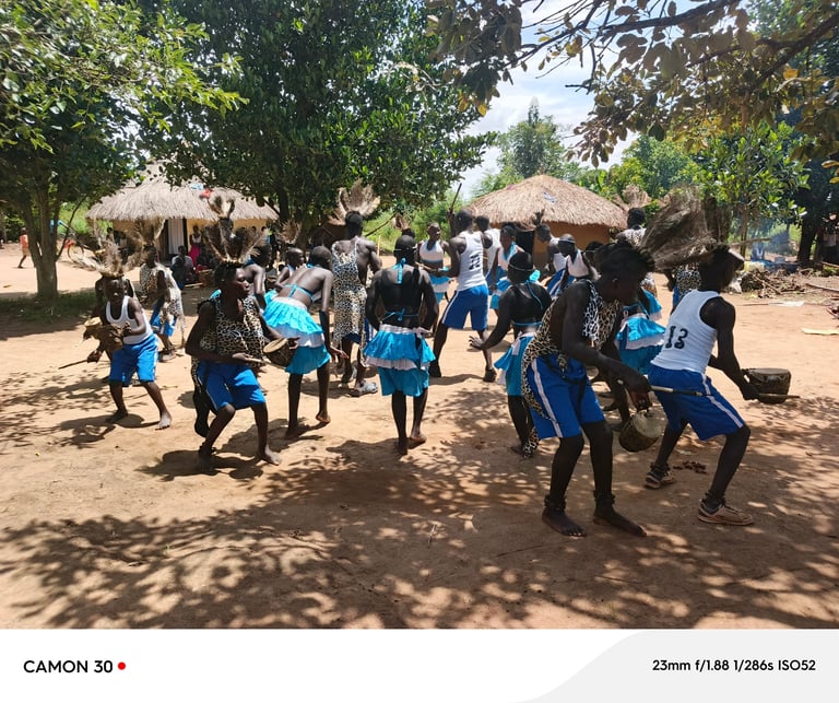Group of children in blue uniforms playing and gathering in a village with thatched roof huts and trees