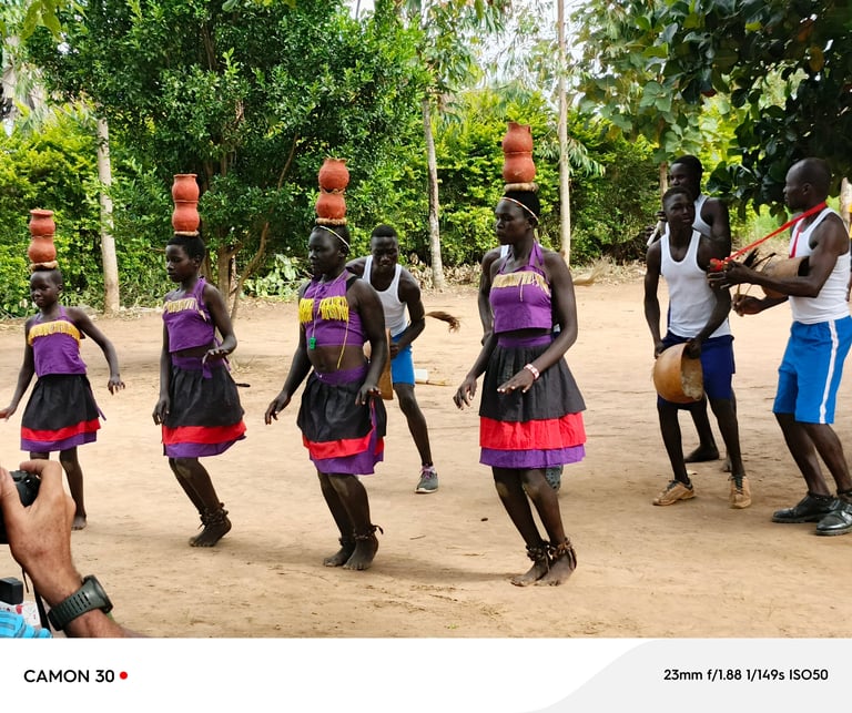 Group of children in purple and pink athletic wear participating in an organized outdoor activity with instructors in a sandy area surrounded by trees